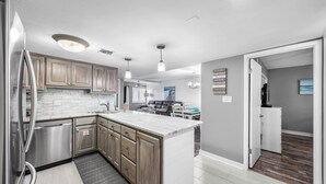 A modern kitchen with wooden cabinets, stainless steel appliances, and a large island. - 620- Time for a trip to the Beach? Rustic, Coastal Beachfront Retreat (Destin)