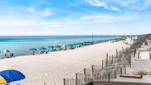 A beach with rows of umbrellas and sun loungers, a wooden fence, and a clear view of the ocean. - 620- Time for a trip to the Beach? Rustic, Coastal Beachfront Retreat (Destin)