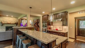 A modern kitchen with granite countertops, bar stools, and stainless steel appliances. - Walk to the Winery! On the Golf Course in Suncadia! Hot Tub | Up to 33% Off!! (Cle Elum)