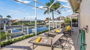 A poolside area with lounge chairs and a view of a water body and surrounding buildings. - Waterfront Home | Pool, Spa & Walk to Beach (Marco Island)