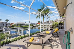 A poolside area with lounge chairs and a view of a water body and surrounding buildings.