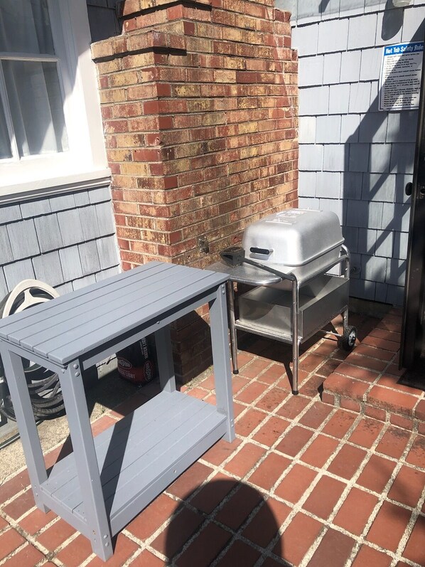 Un patio con una mesa de metal y una parrilla para barbacoa.