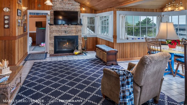 A cozy living room with a fireplace, wooden walls, and a checkered rug.