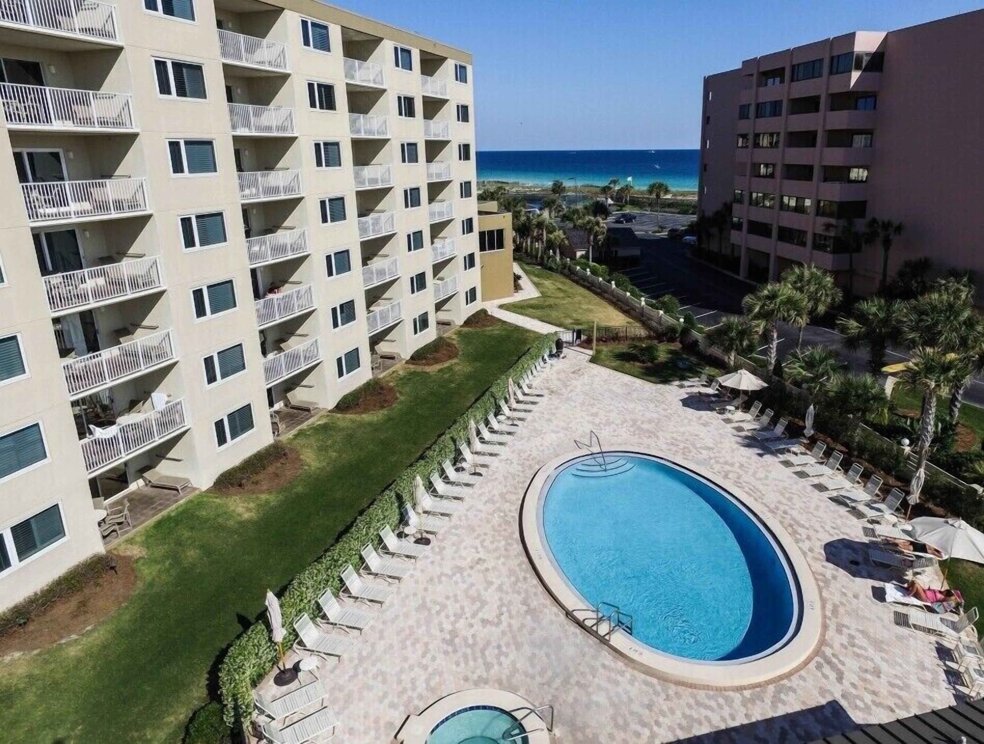 A hotel with multiple balconies, a swimming pool, and a view of the ocean.