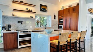 A modern kitchen with a marble island, wooden cabinets, and a built-in oven.