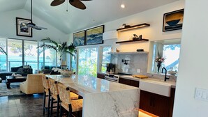 A modern kitchen with a marble countertop, built-in appliances, and a large window overlooking a scenic view.
