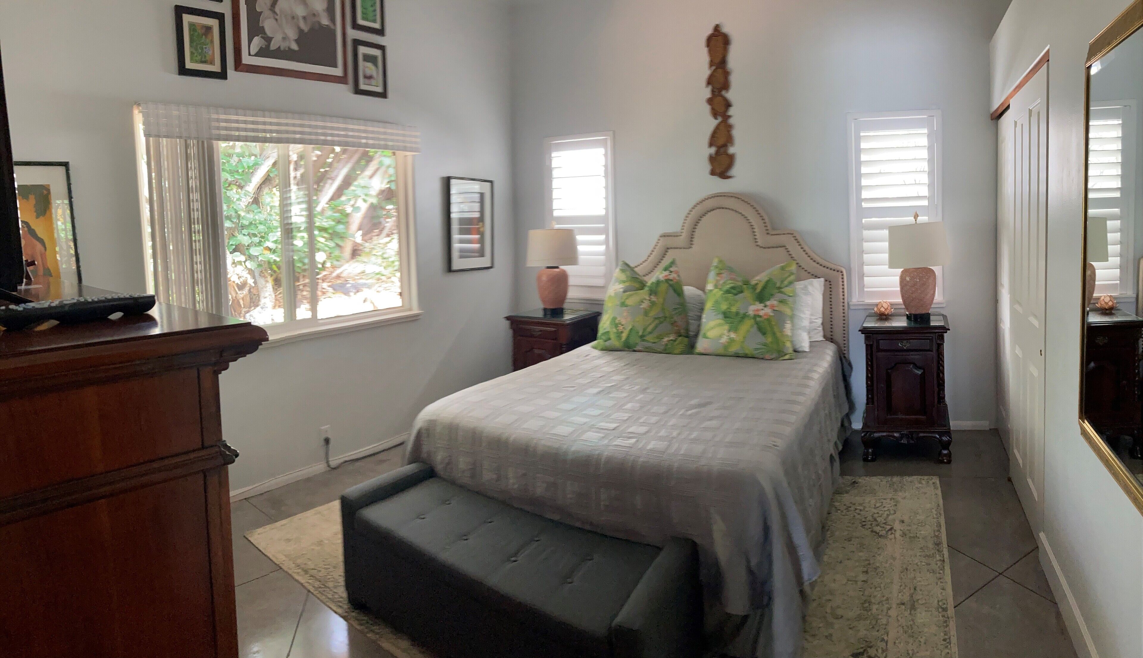 A bedroom with a bed, bedside tables, a dresser, a window, and a mirror.