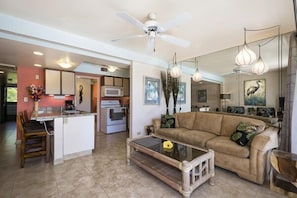 A spacious living area with a sofa, coffee table, and a kitchen in the background.