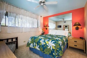 Un dormitorio con cama, mesita de noche, espejo y ventilador de techo.