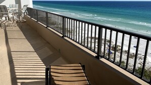 Un balcon avec vue sur l’océan, une balustrade et plusieurs chaises.