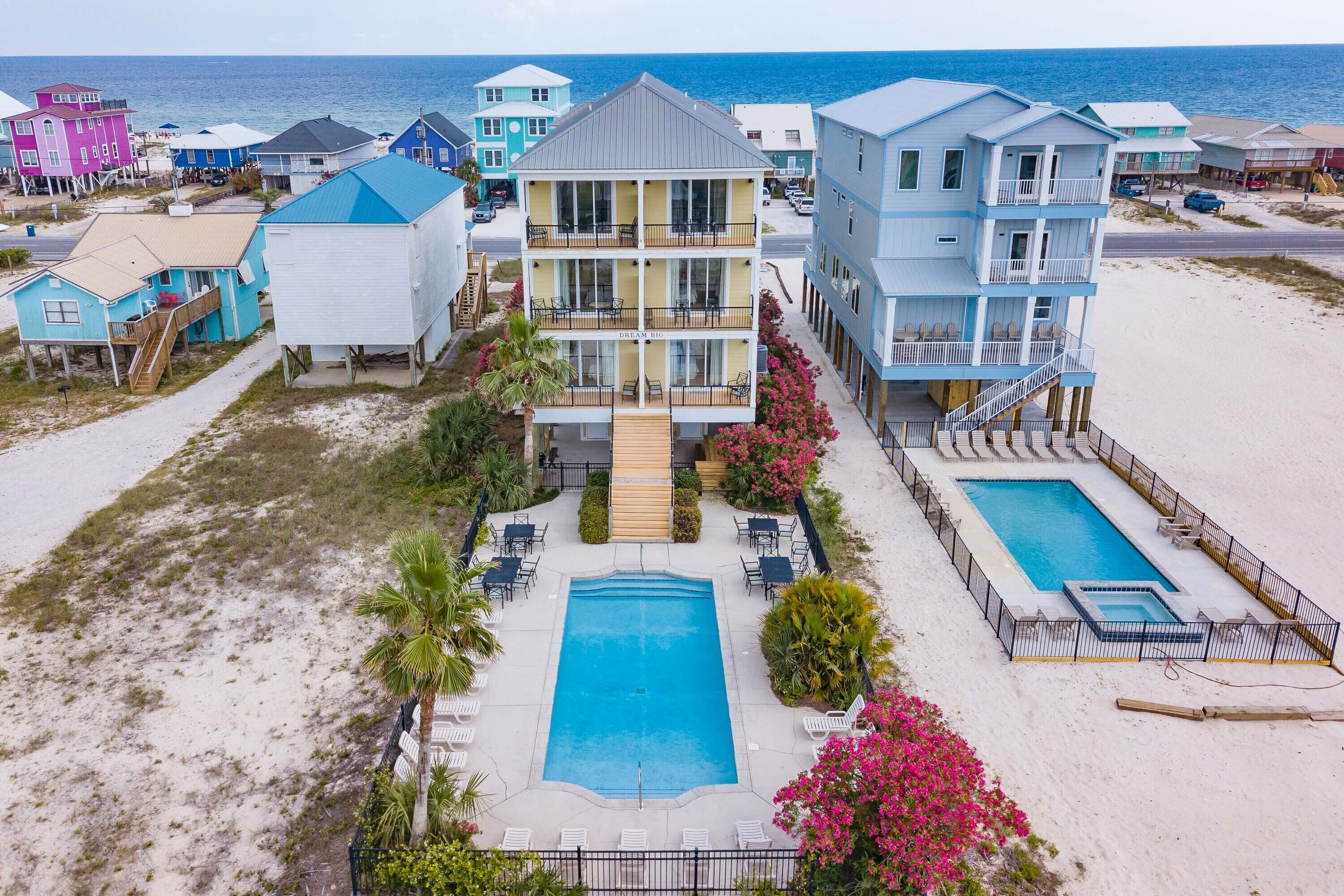 A beachfront hotel with multiple stories, a central pool, and a beachside view.