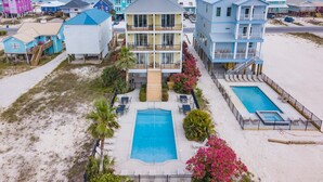 A beachfront hotel with multiple stories, a central pool, and a beachside view. - Dream Big by GSVR | Beachview Family Reunion Home w/ Big Pool & Elevator + FREE Activities/Golf (Gulf Shores)