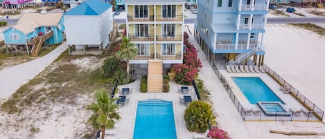 A beachfront hotel with multiple stories, a central pool, and a beachside view.