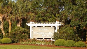 Schild mit der Aufschrift Wrightsville Beach, mit einem Pergola-Struktur und üppigem Grün.