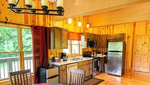 A wooden cabin kitchen with a dining table, chairs, and a refrigerator. - Lily Pad - Hosted by The Chalets (Logan)