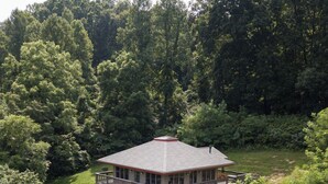 A two-story cabin with a balcony, surrounded by dense forest. - Lily Pad - Hosted by The Chalets (Logan)
