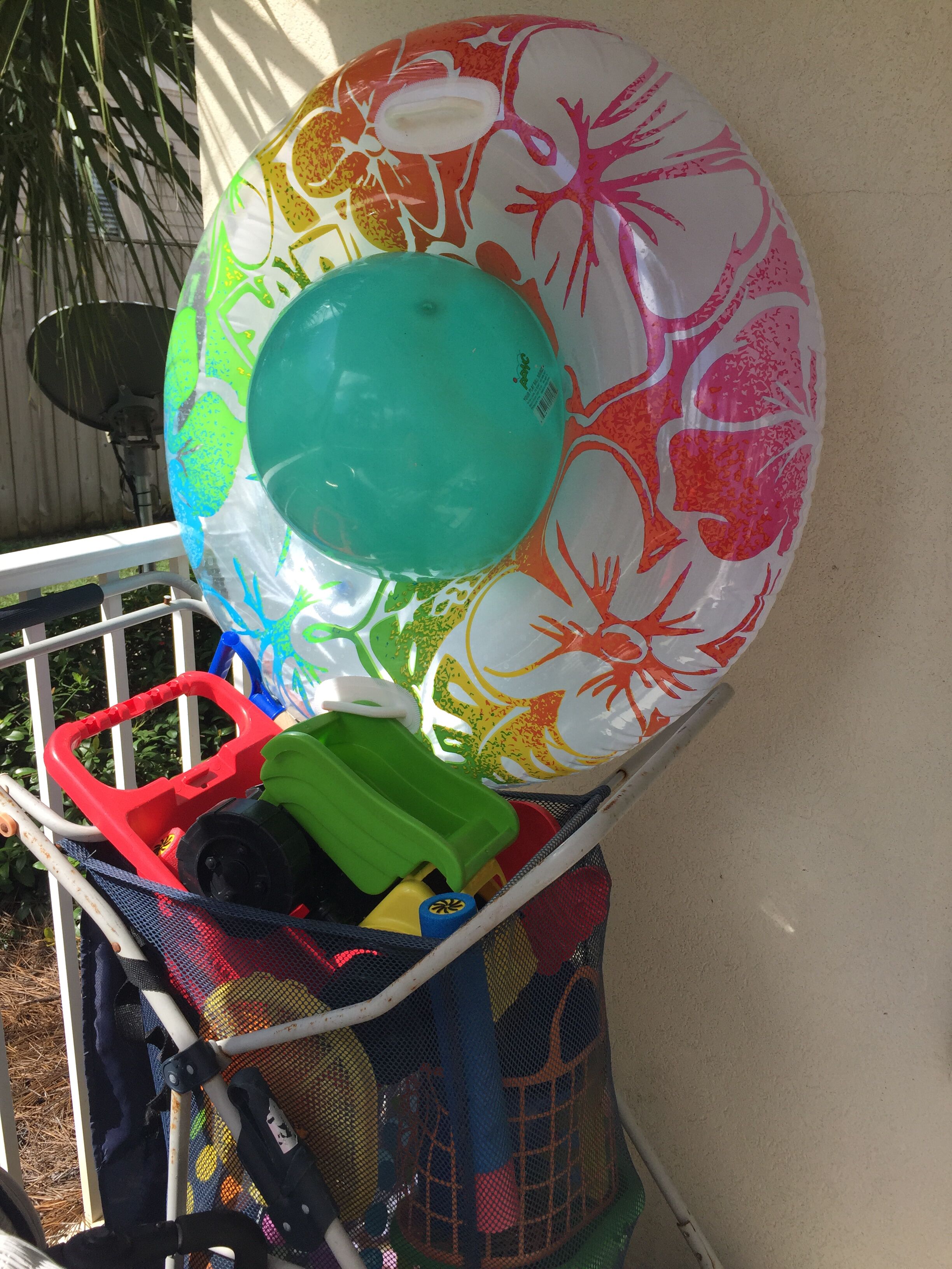 A colorful beach ball and a green toy in a basket.