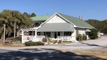 A white building with a green roof and a striped awning, featuring a sign that reads "Angelina's Pizzeria & Pasta."