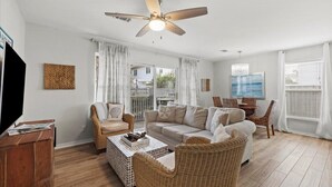 A spacious living room with a large sofa, two armchairs, a coffee table, and a ceiling fan.