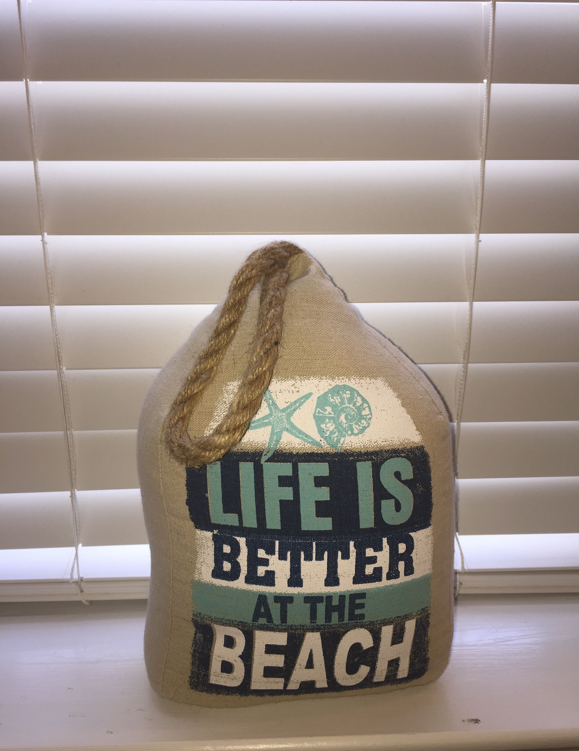 Un oggetto decorativo con la scritta “LIFE IS BETTER AT THE BEACH” e un disegno di stella marina.