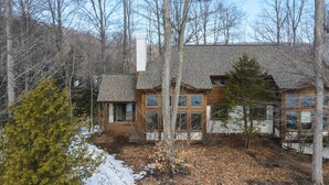 Une maison à deux étages, dotée d’un toit en pente, de grandes fenêtres et d’une cheminée.