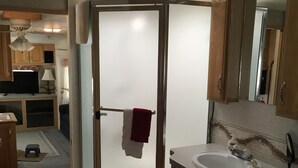 Een kleine badkamer met een douchecabine van glas, een wastafel en een spiegel.