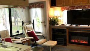 Een gezellig RV-interieur met een zithoek, een televisie en een open haard.