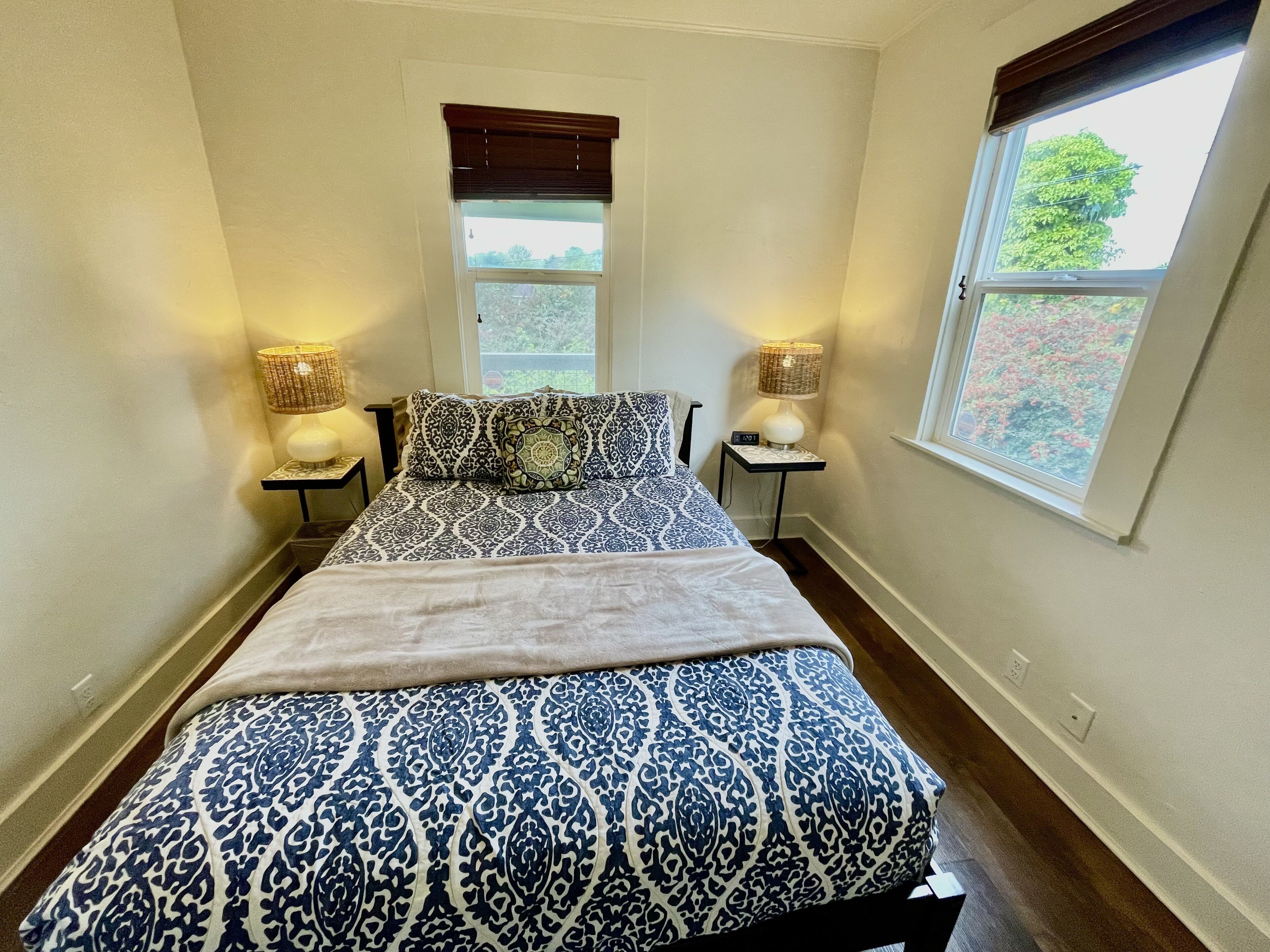 A bedroom with a bed, two bedside tables with lamps, a window, and a door.
