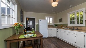 Una cocina con armarios blancos, una mesa de madera y un refrigerador.