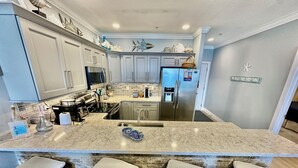 Una cocina moderna con gabinetes grises, electrodomésticos de acero inoxidable y una isla central con taburetes de bar.