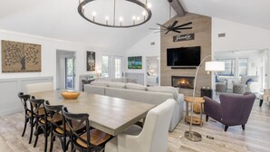 A spacious living area with a large sofa set, a dining table with chairs, and a fireplace.