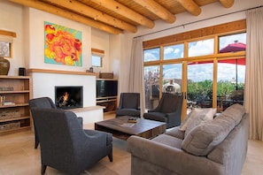 A living room with a fireplace, sofas, armchairs, and a TV.