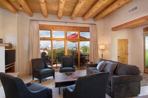 A spacious living room with a large window, wooden ceiling beams, and a cozy seating area.