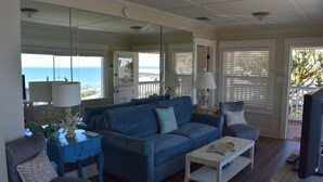 A living room with a blue sofa, a coffee table, and a television. There is a window with a view of the ocean. - Breathtaking Ocean and Beach Views (Avila Beach)