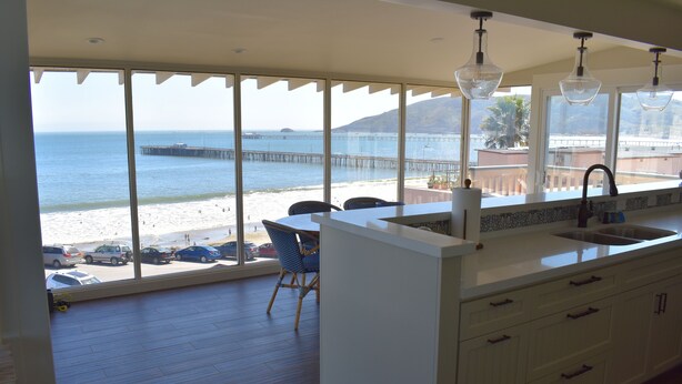 A kitchen with a large window overlooking a beach and pier. - Breathtaking Ocean and Beach Views (Avila Beach)