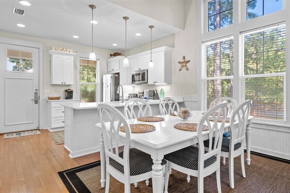 A spacious kitchen with white cabinetry, a central island, and pendant lighting.