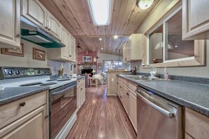 A kitchen with wooden cabinets, a stainless steel stove, and a large window.