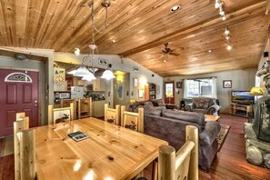 A spacious living area with a wooden ceiling, a dining table, and a cozy seating arrangement.