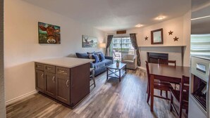 Un espacio habitable compacto con kitchenette, un sofá, una mesa de comedor y obras de arte en las paredes.