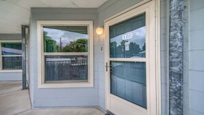 Entrada de una casa con puerta marcada '108', una ventana y un porche.