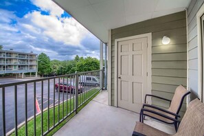 Een balkon met uitzicht op een parkeerplaats en een gebouw aan de overkant van de straat.