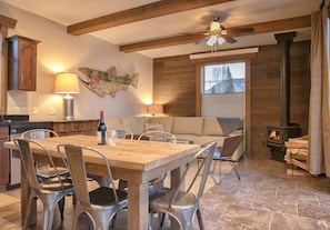 A dining area with a wooden table and chairs, a sofa, and a fireplace.