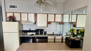 Une cuisine compacte équipée d’un réfrigérateur, d’une cuisinière, d’un four à micro-ondes et d’une table à manger avec deux chaises.