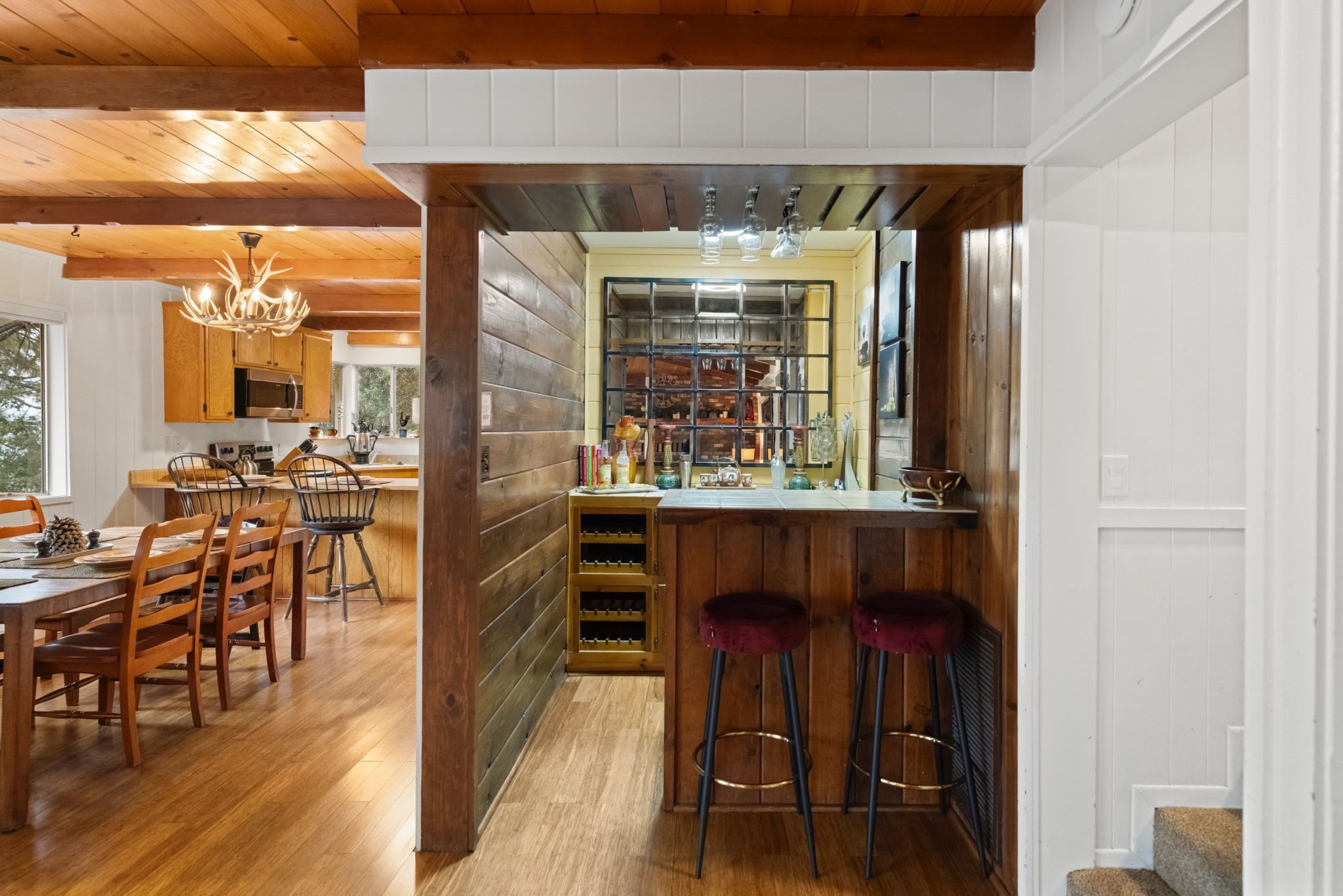 A modern kitchen with wooden cabinetry, a central island with stools, and a wine rack.