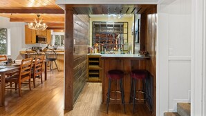 A modern kitchen with wooden cabinetry, a central island with stools, and a wine rack. - Three Gazing Stars: Spacious, Stunning Views, Walk-to-Town, A/C (Idyllwild)