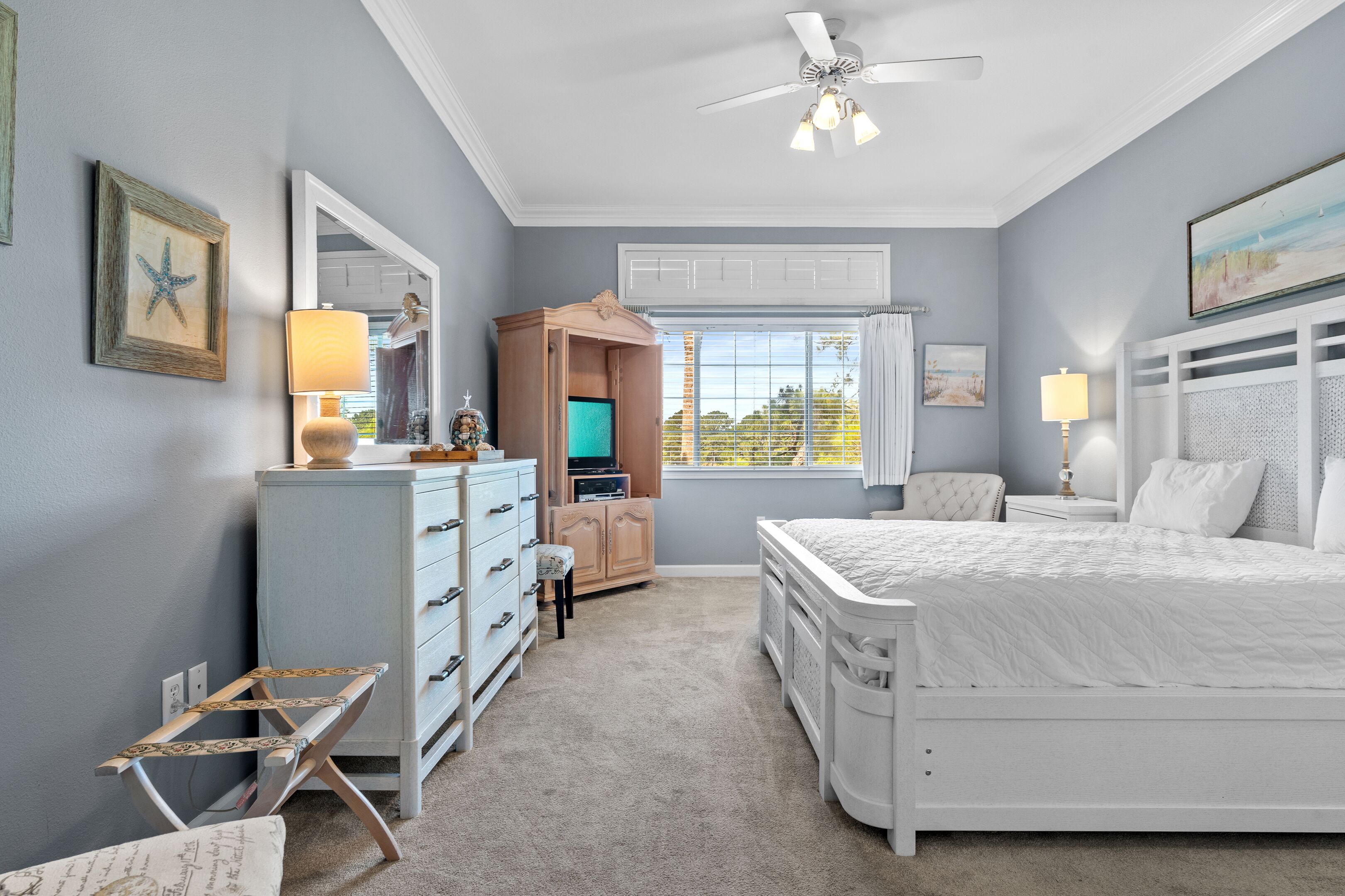 Une chambre à coucher comprenant un lit, une commode, une coiffeuse et un téléviseur.