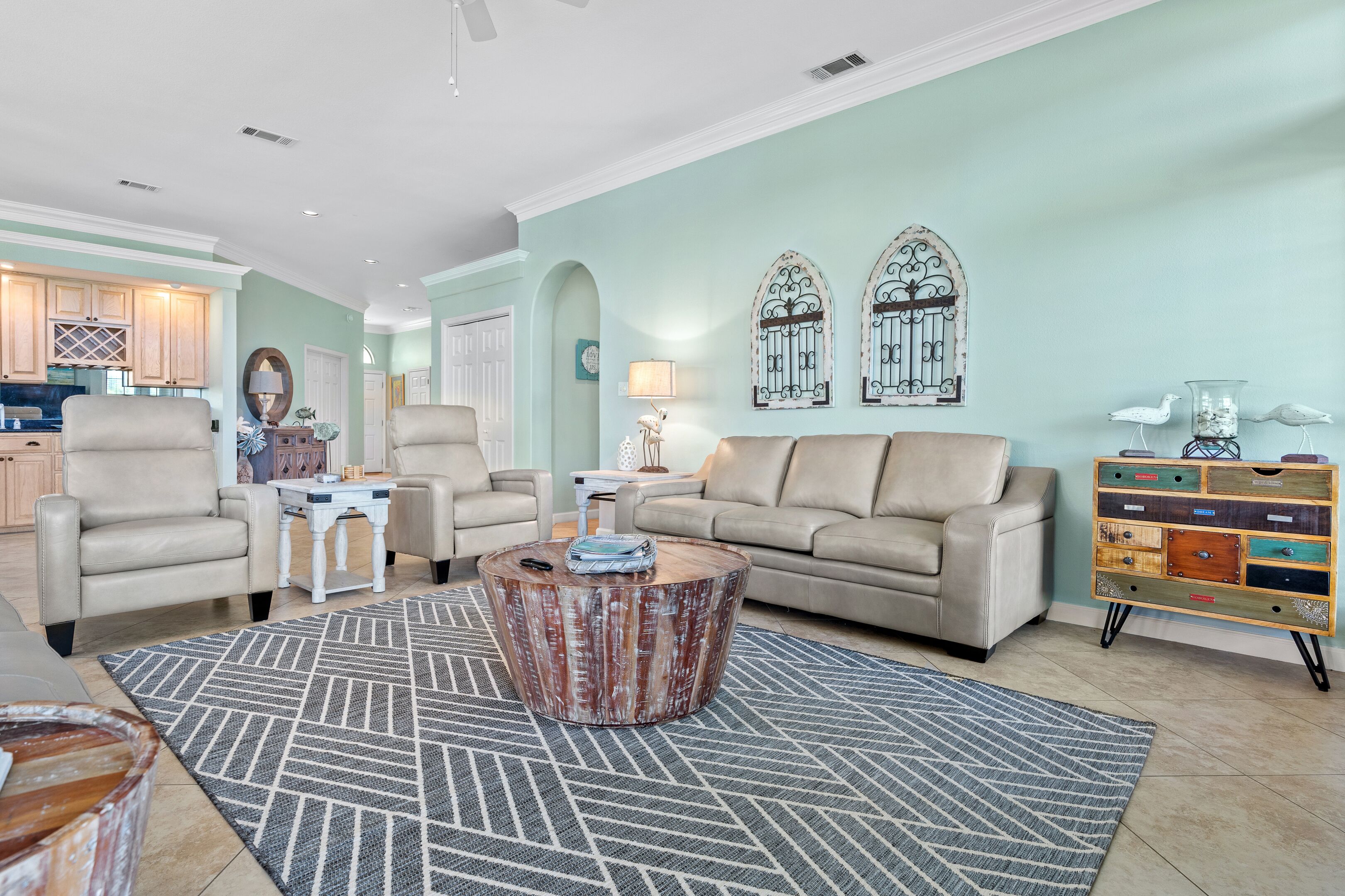 Una sala de estar con un sofá color beige, dos sillones, una mesa de centro y un aparador decorativo.