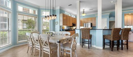 A spacious kitchen with wooden cabinets, a central island, and a dining area with a table and chairs.