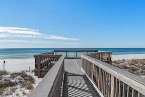 Une promenade en bois qui mène à une plage d’où l’on a une vue dégagée sur l’océan.