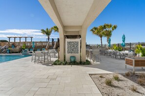 Relax by the pool surrounded by a patio with lounge chairs and tables under a pergola.